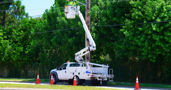 Person in bucket truck next to power pole