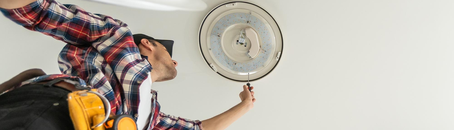 Below view of a man installing a recessed light fixture